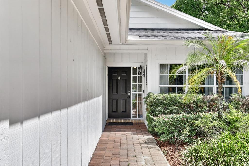A brick walkway leads to a black front door of a white house with landscaping — 1741 MIZELL AVENUE, WINTER PARK, FL