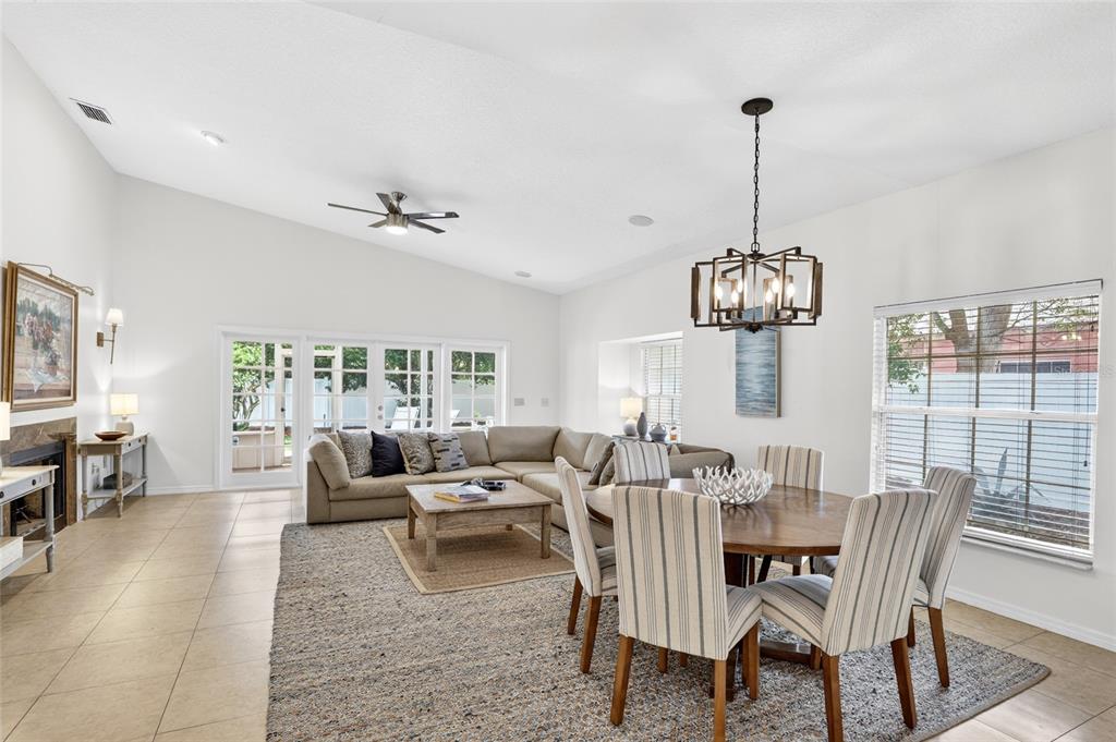A living and dining area features vaulted ceilings, tile flooring, a sectional sofa, and chandelier — 1741 MIZELL AVENUE, WINTER PARK, FL