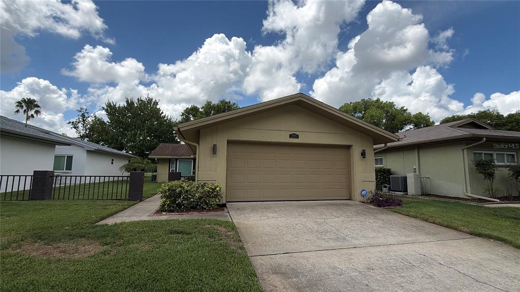A tan single-story house with a two-car garage and a concrete driveway — 7800 FAIRLAWN DRIVE, HUDSON, FL