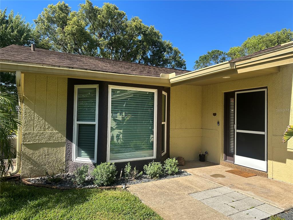 The exterior of a yellow house features a bay window and a covered front entryway — 7800 FAIRLAWN DRIVE, HUDSON, FL