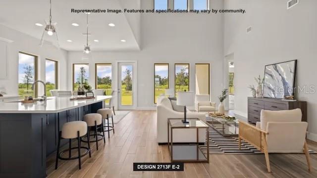 This rendering shows an open-concept kitchen and living area with light wood floors and high ceilings — 13062 CAMELOT LANE, PUNTA GORDA, FL