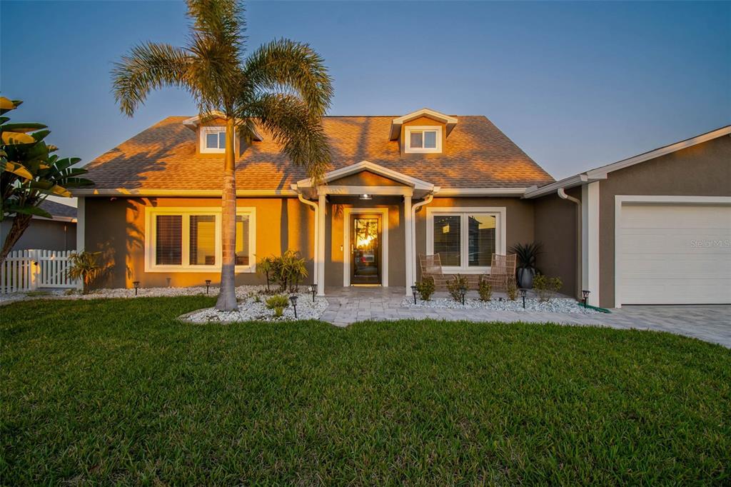 A single-story house with a palm tree, white fence, and attached garage at sunset — 8034 BRIGHTON DRIVE, PORT RICHEY, FL