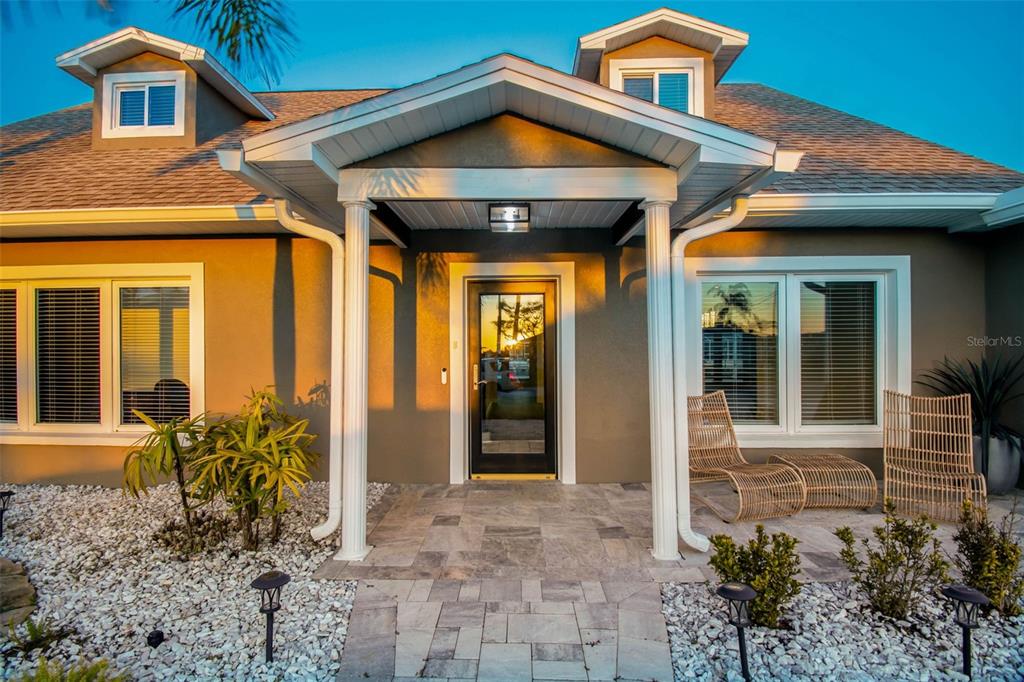 The exterior of a house features a covered entryway with white columns and stone pavers — 8034 BRIGHTON DRIVE, PORT RICHEY, FL