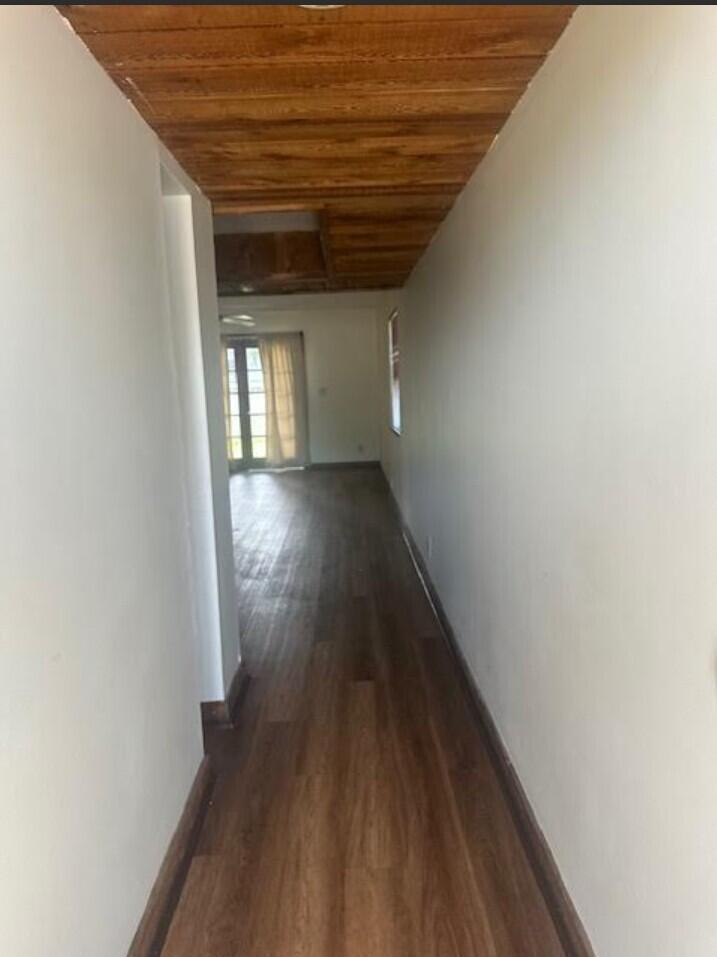 A narrow hallway with wood-plank ceiling and flooring leads toward a room with glass doors — 5922 Thomas Street, Hollywood FL 33021, HOLLYWOOD, FL