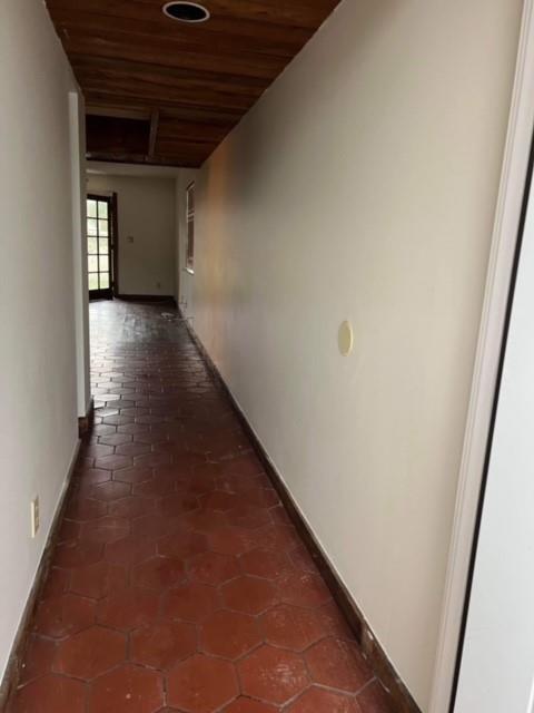 A hallway with hexagonal terracotta floor tiles and a wood-paneled ceiling leads to a doorway — 5922 Thomas Street, Hollywood FL 33021, HOLLYWOOD, FL