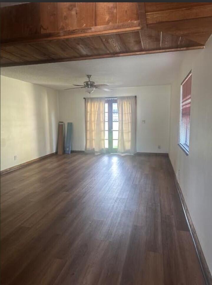 An empty living room features wood-look flooring, a wood-paneled ceiling beam, and glass patio doors — 5922 Thomas Street, Hollywood FL 33021, HOLLYWOOD, FL