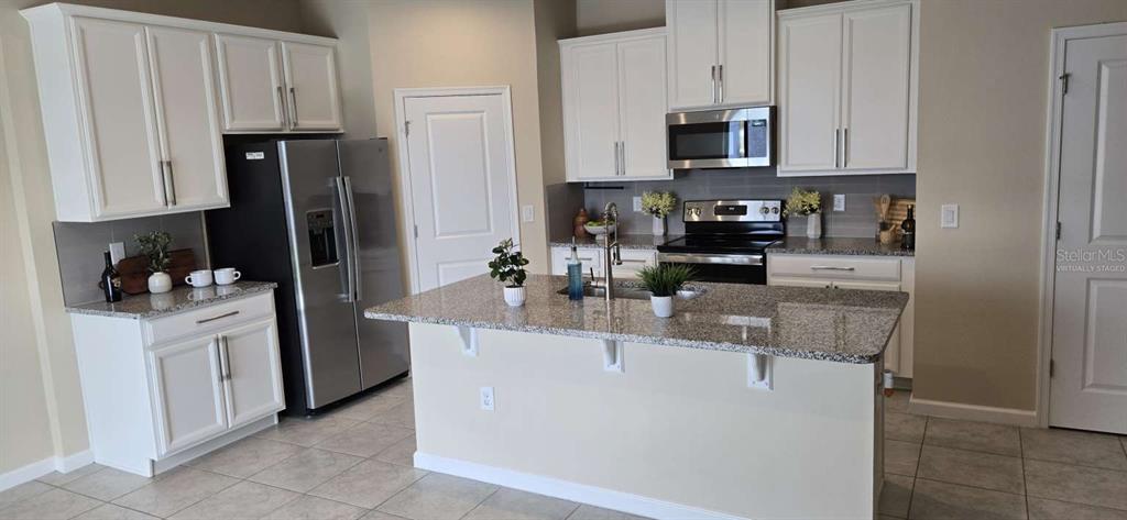 A kitchen features white cabinets, granite countertops, stainless steel appliances, and a central island — 1564 EUCALYPTUS WAY, DAVENPORT, FL