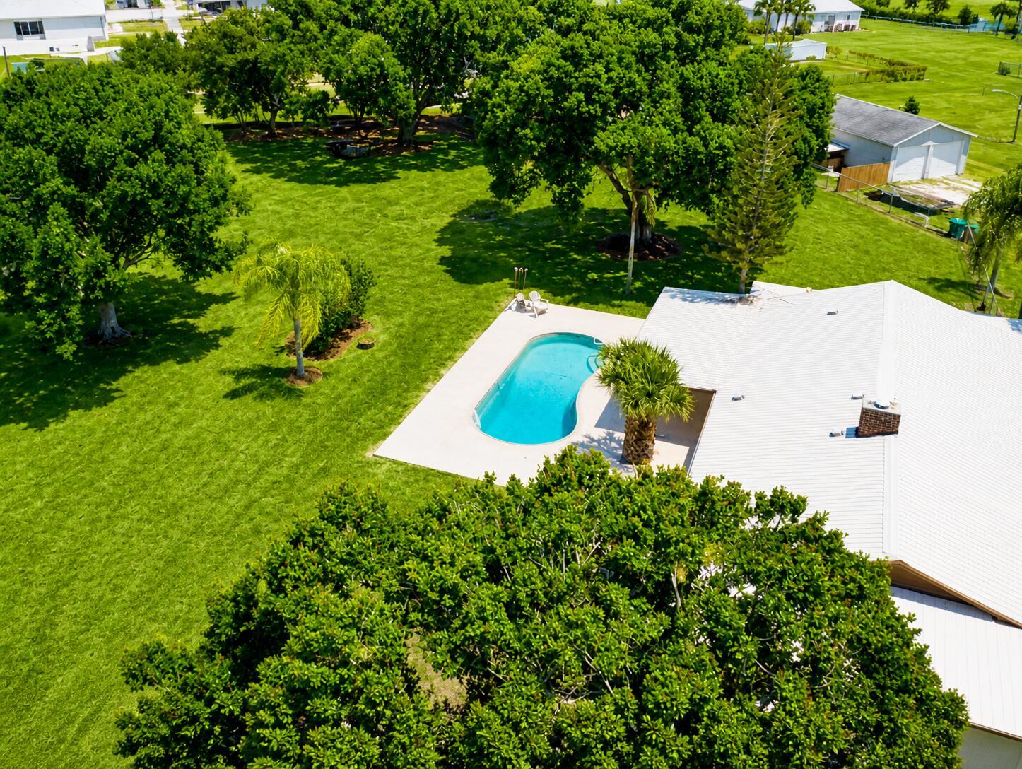 An aerial view shows a house with a swimming pool, large lawn, and mature trees — 3856 SW 11th Avenue, Okeechobee FL 34974, OKEECHOBEE, FL
