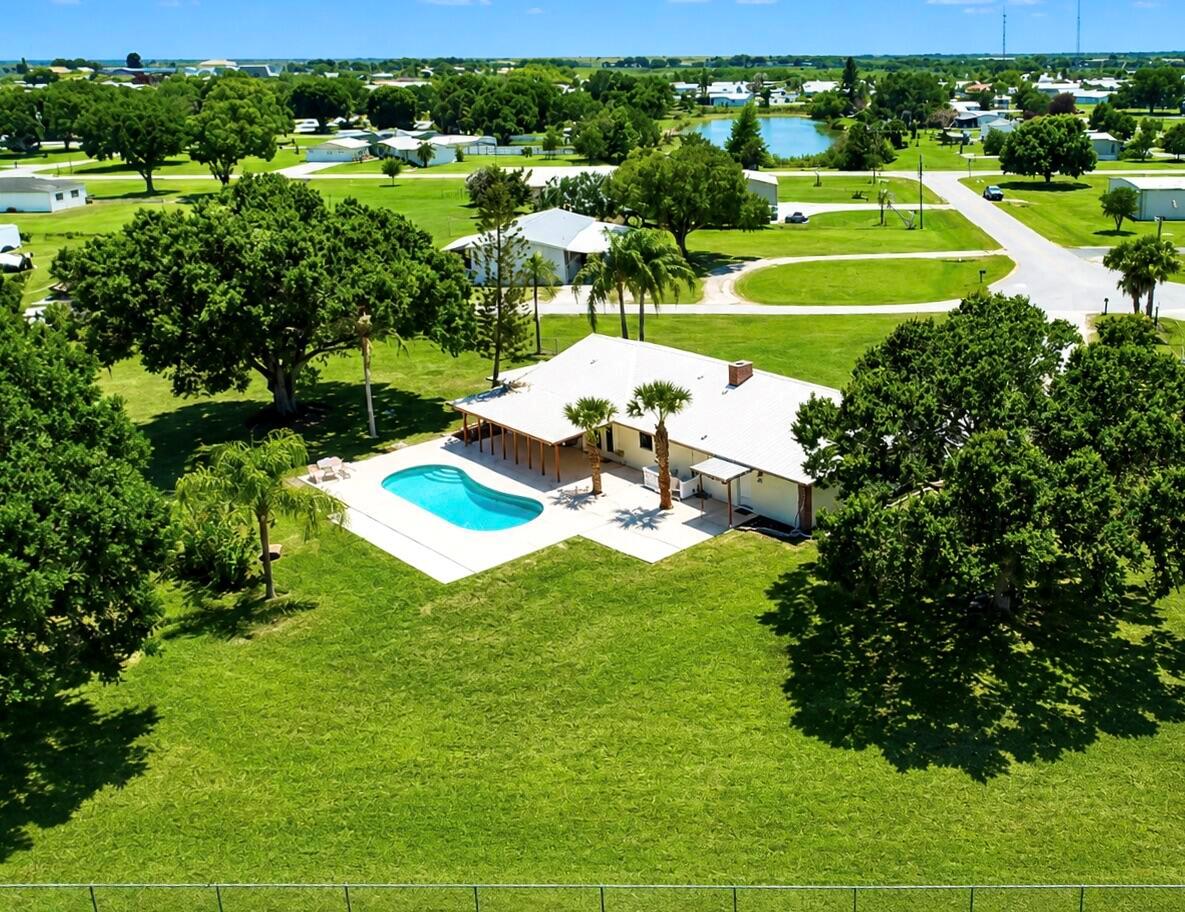An aerial view of a house with a swimming pool, patio, and large grassy yard — 3856 SW 11th Avenue, Okeechobee FL 34974, OKEECHOBEE, FL