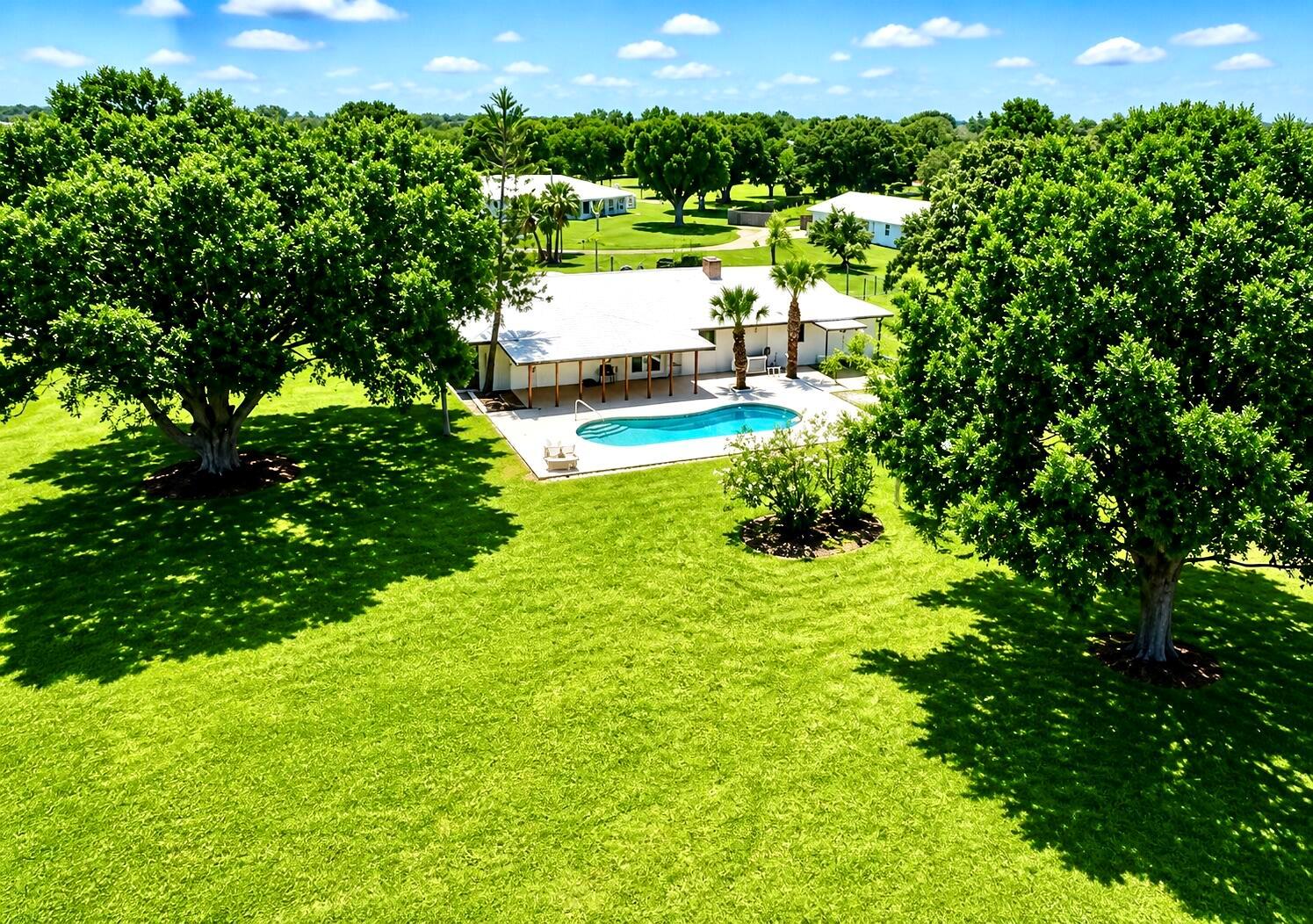 An aerial view shows a white house with a swimming pool and large shade trees — 3856 SW 11th Avenue, Okeechobee FL 34974, OKEECHOBEE, FL