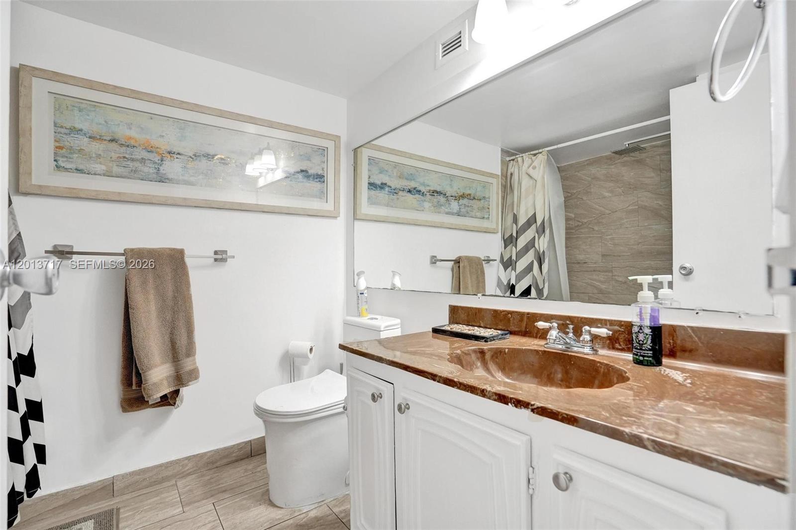 A bathroom features a white vanity with a brown marble countertop and a large mirror — 2017 S Ocean Dr # 205, Hallandale Beach FL 33009, HALLANDALE BEACH, FL