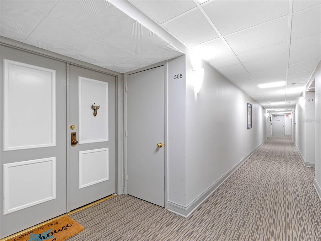 A hallway with gray doors, a patterned carpet, and a drop ceiling in an apartment building — 1460 GULF BOULEVARD UNIT 308, CLEARWATER BEACH, FL