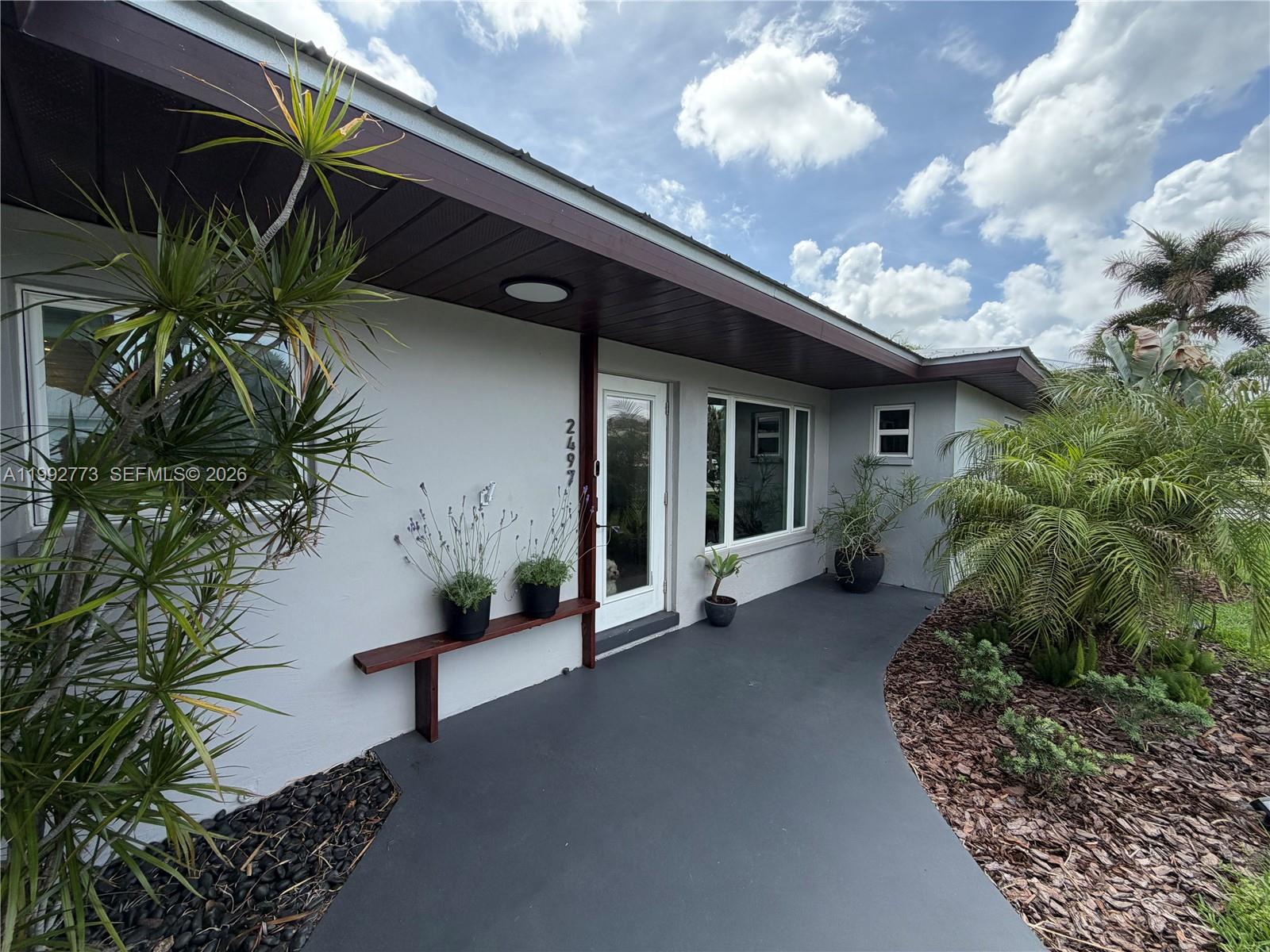 A single-story house with a white metal roof, gray exterior, and a two-car garage — 2497 NW South Manor Ave, Stuart FL 34994, STUART, FL