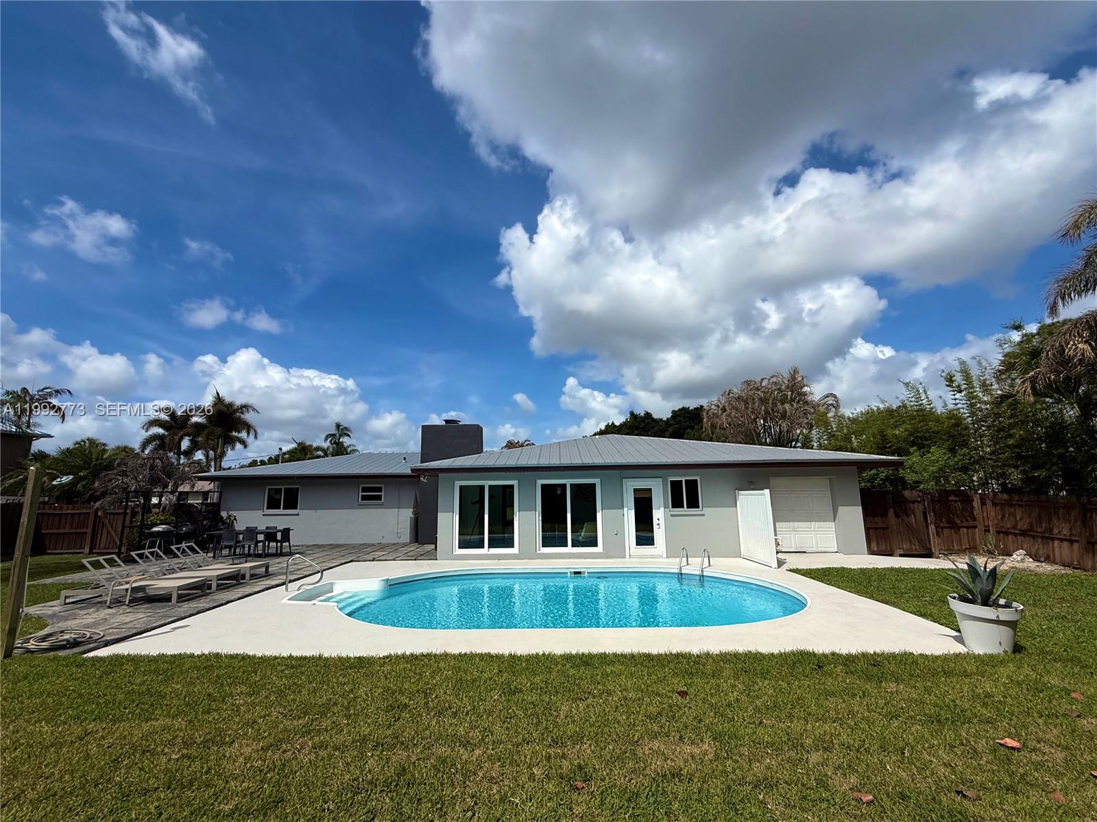 The exterior of a house features a gray painted porch, a wooden bench, and landscaping — 2497 NW South Manor Ave, Stuart FL 34994, STUART, FL