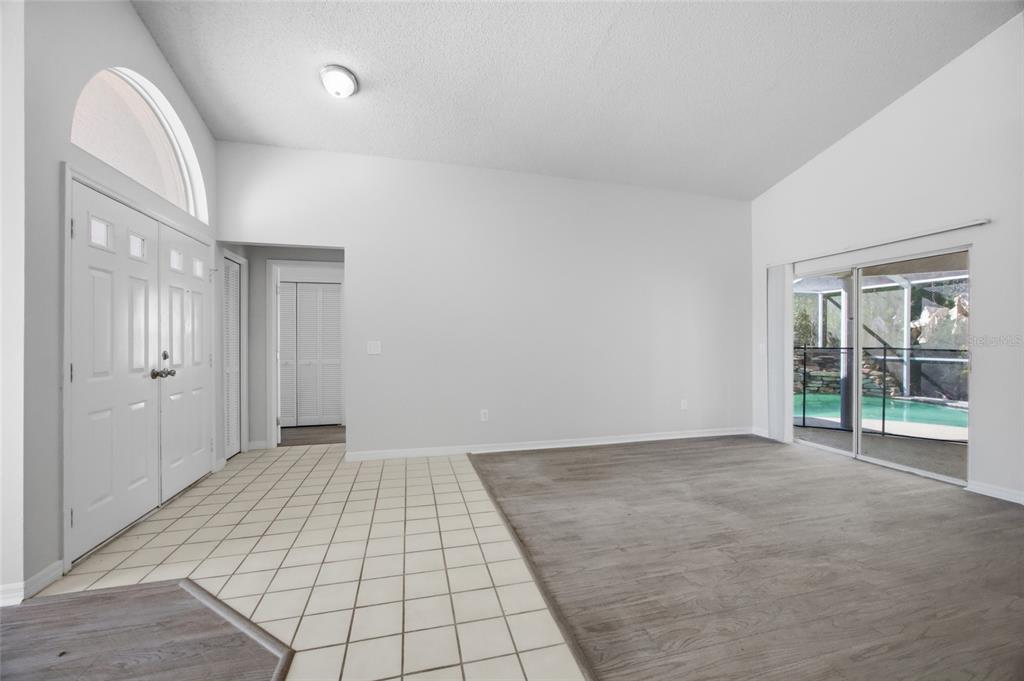 A living room with tile flooring near the entrance, wood-look flooring, and sliding glass doors — 812 CRESTRIDGE DRIVE, TARPON SPRINGS, FL