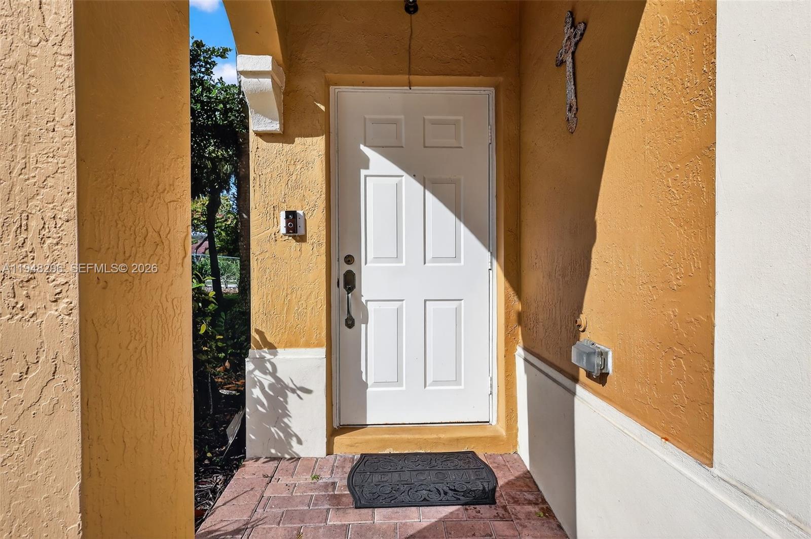 A white front door with a six-panel design is set within a yellow stucco entryway — 3160 SW 129th Ter # 118, Miramar FL 33027, MIRAMAR, FL