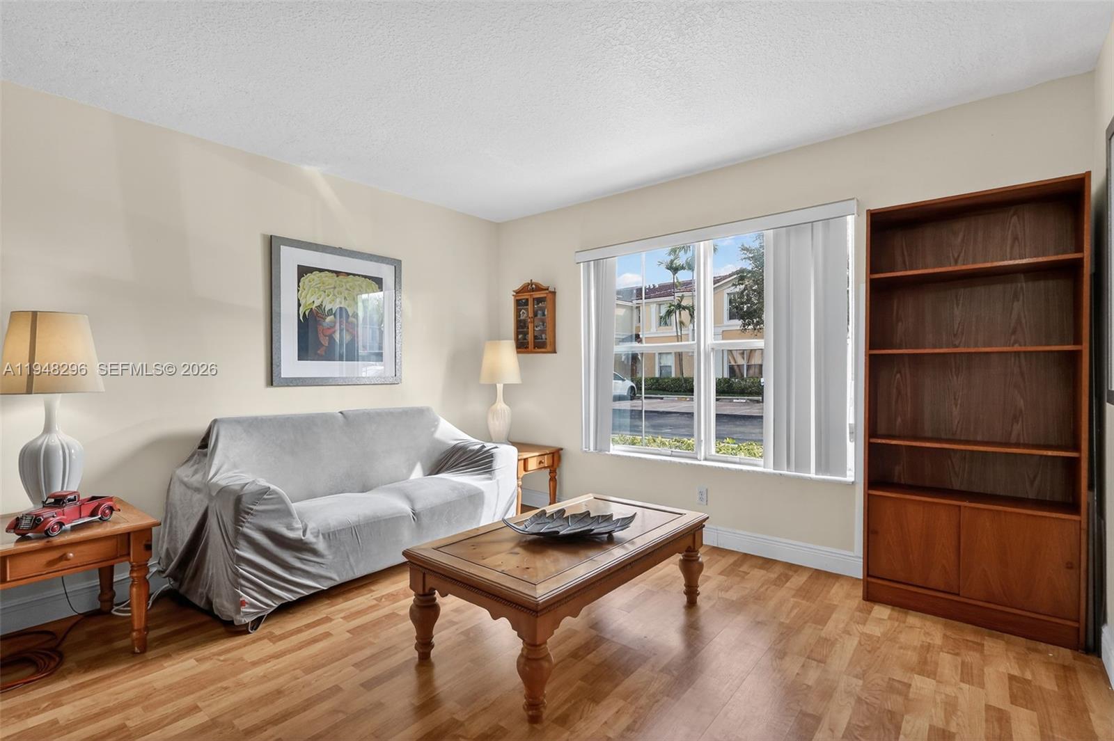 A living room features a covered sofa, wooden coffee table, bookshelf, and light-colored flooring — 3160 SW 129th Ter # 118, Miramar FL 33027, MIRAMAR, FL