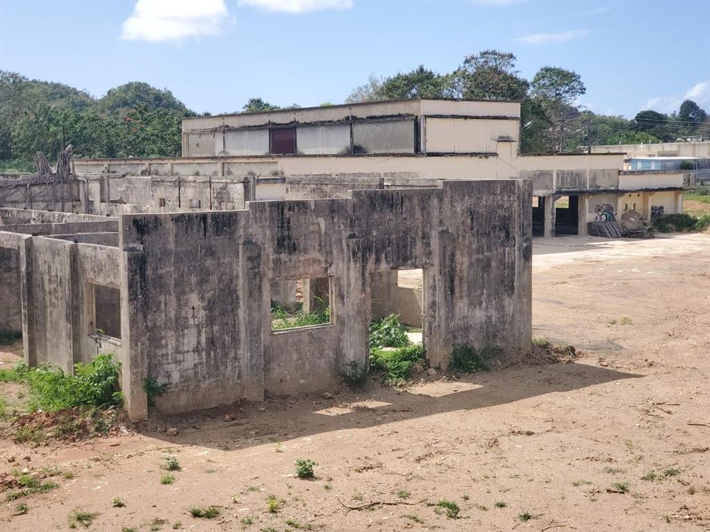 An exterior view of a dilapidated concrete building structure with open windows and dirt surroundings — 670 N COTO SUR, MANATI, PR