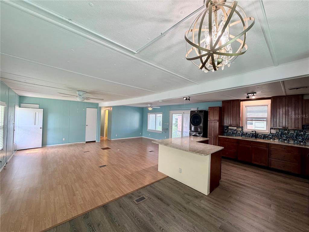 An open-concept living area features light blue walls, wood-look flooring, and a kitchen with dark cabinets — 9790 66TH STREET N UNIT 100, PINELLAS PARK, FL