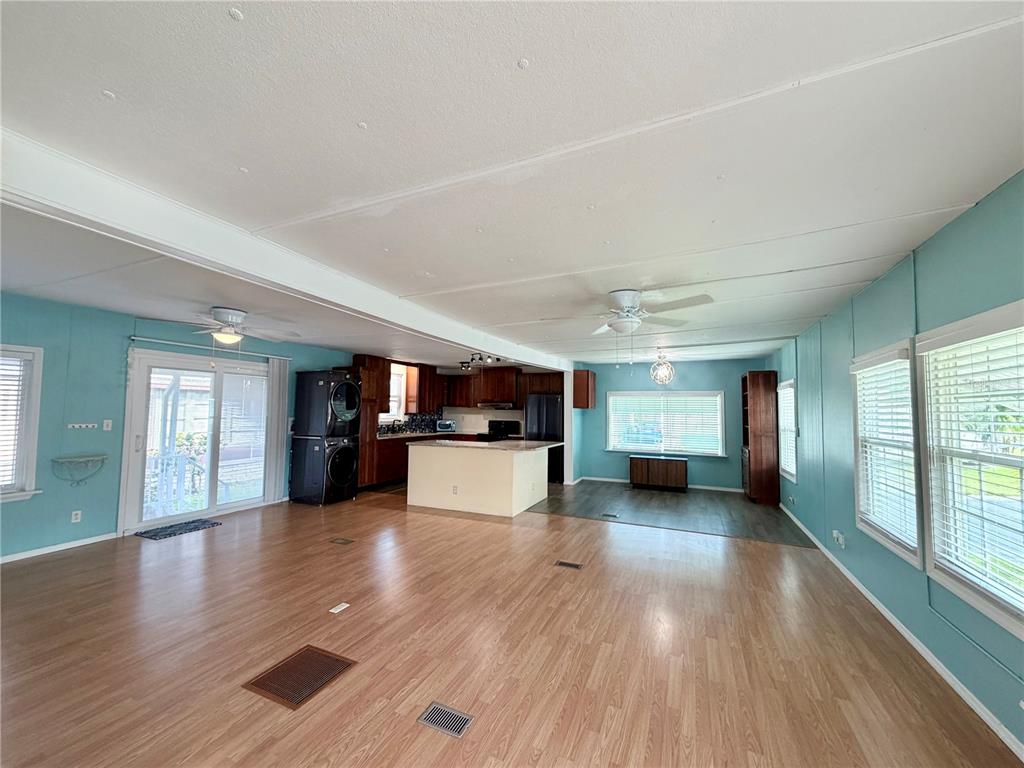 An open-concept living and kitchen area features light wood flooring, blue walls, and white cabinetry — 9790 66TH STREET N UNIT 100, PINELLAS PARK, FL
