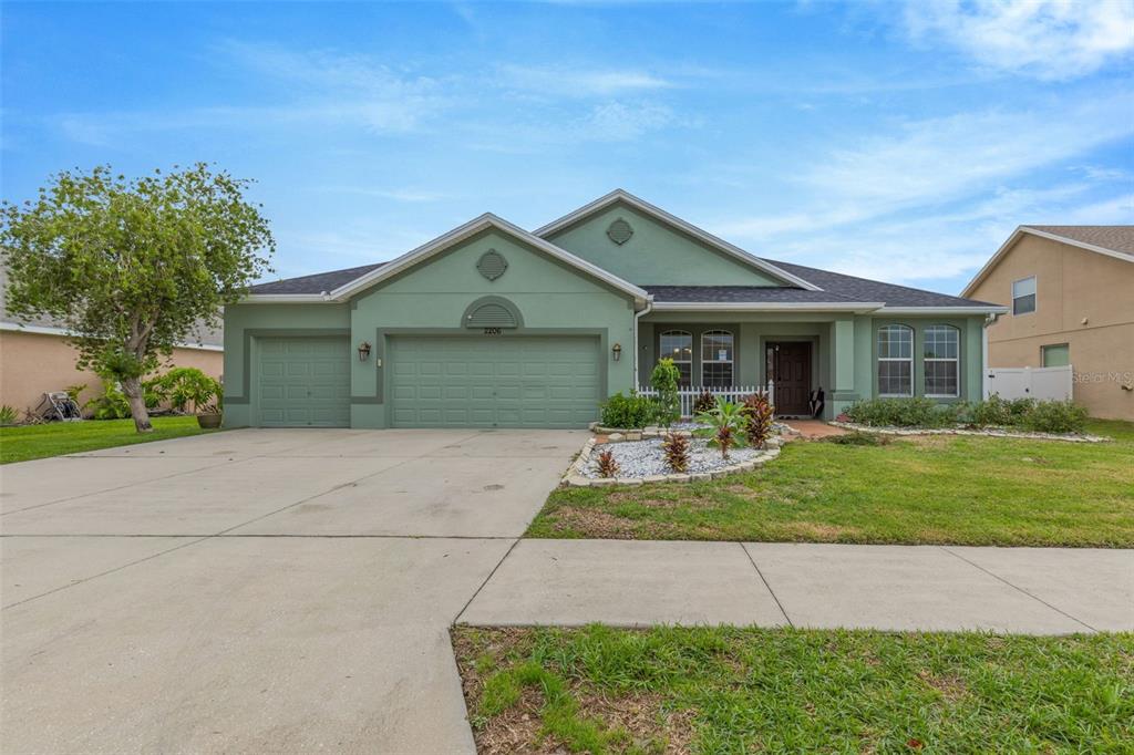 A single-story green house with a three-car garage and a concrete driveway — 2206 VIA CORTONA STREET, PLANT CITY, FL