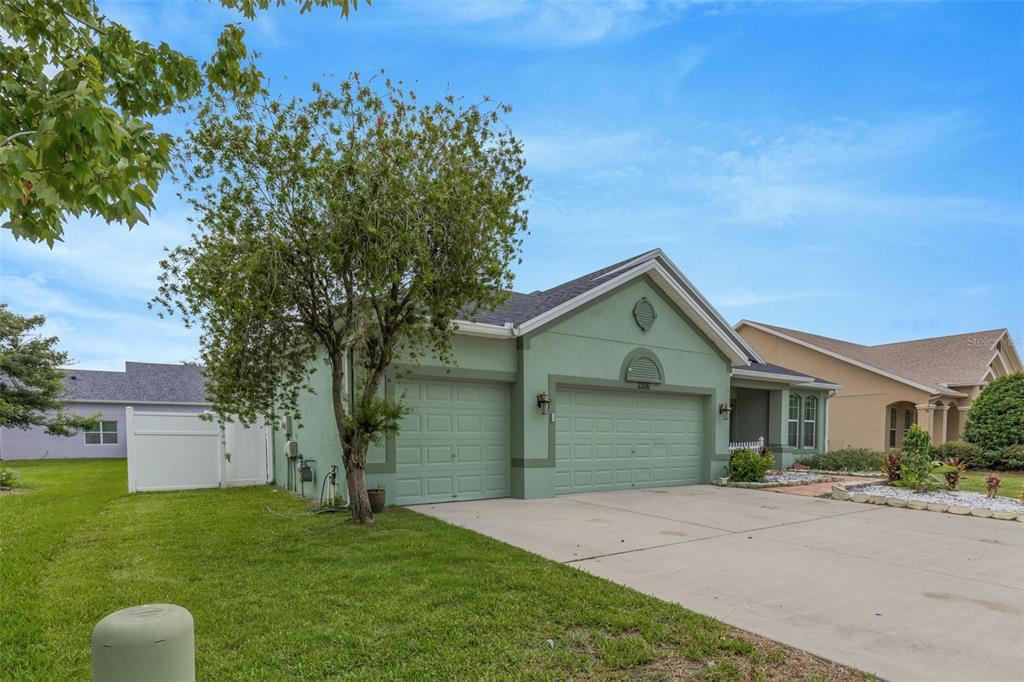 A light green single-story house with a two-car garage and a front lawn — 2206 VIA CORTONA STREET, PLANT CITY, FL