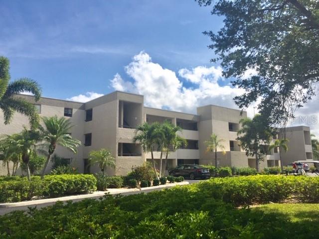 A multi-story beige apartment building is surrounded by palm trees and manicured landscaping — 801 ISLAMORADA BOULEVARD UNIT 22B, PUNTA GORDA, FL