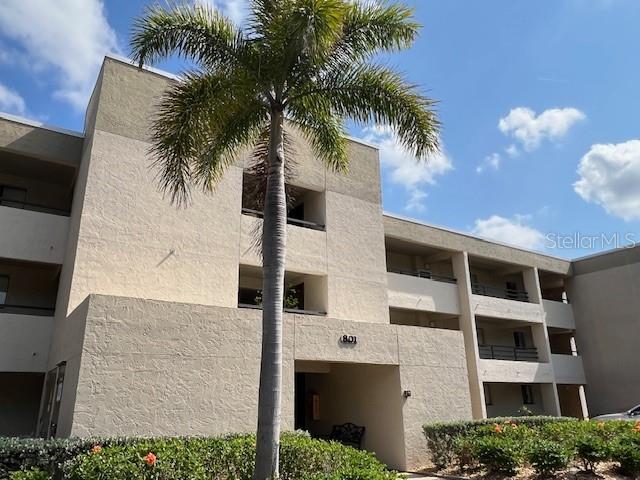 A three-story tan stucco apartment building features balconies and a palm tree in front — 801 ISLAMORADA BOULEVARD UNIT 22B, PUNTA GORDA, FL