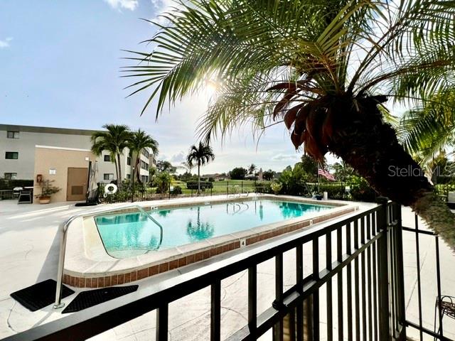 A swimming pool sits on a patio next to a building with palm trees — 801 ISLAMORADA BOULEVARD UNIT 22B, PUNTA GORDA, FL