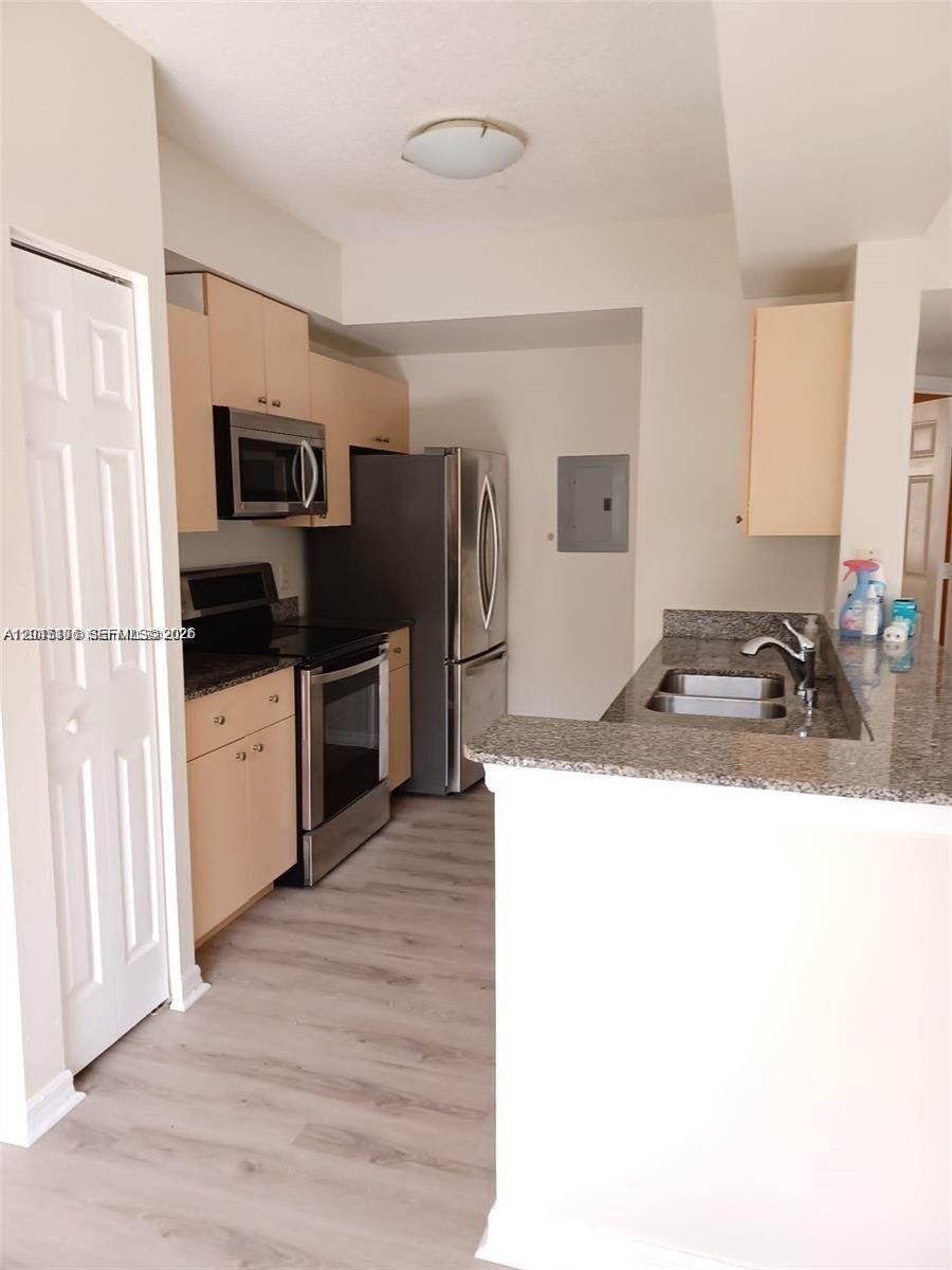 A kitchen features light wood cabinets, granite countertops, stainless steel appliances, and wood-look flooring — 2493 Centergate Dr # 204, Miramar FL 33025, MIRAMAR, FL