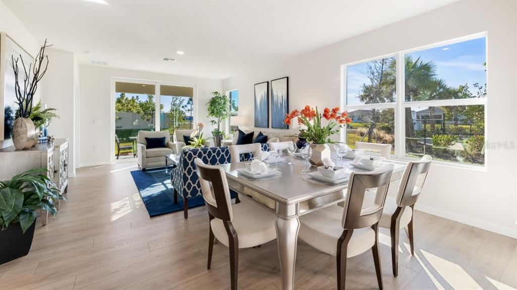 A bright open-concept living and dining area with wood-look flooring and a view of fields — 7366 SW 45TH COURT, OCALA, FL