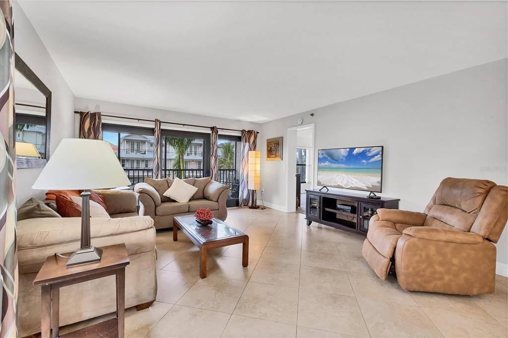 A living room features tile flooring, a brown sofa, a recliner, and a television console — 1001 BENJAMIN FRANKLIN DRIVE UNIT 201, SARASOTA, FL