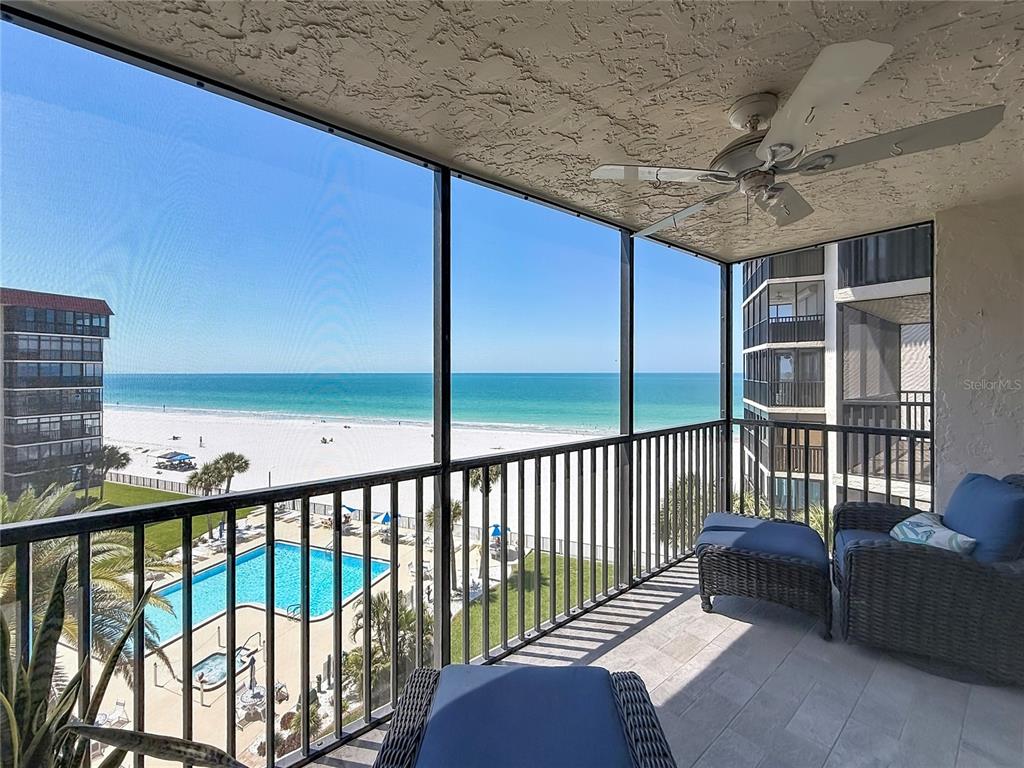 A screened-in balcony overlooks a swimming pool, sandy beach, and the ocean — 18304 GULF BOULEVARD UNIT 505, REDINGTON SHORES, FL