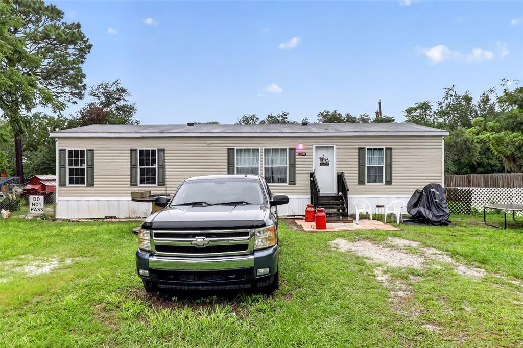 A single-story manufactured home with beige siding sits behind a parked pickup truck — 5576 S SHALIMAR POINT, HOMOSASSA, FL