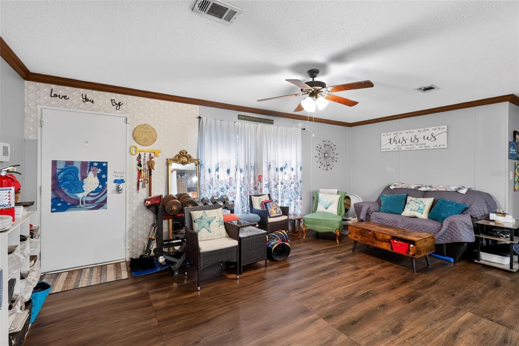 A living room features wood-look flooring, a ceiling fan, a sofa, and a front door — 5576 S SHALIMAR POINT, HOMOSASSA, FL