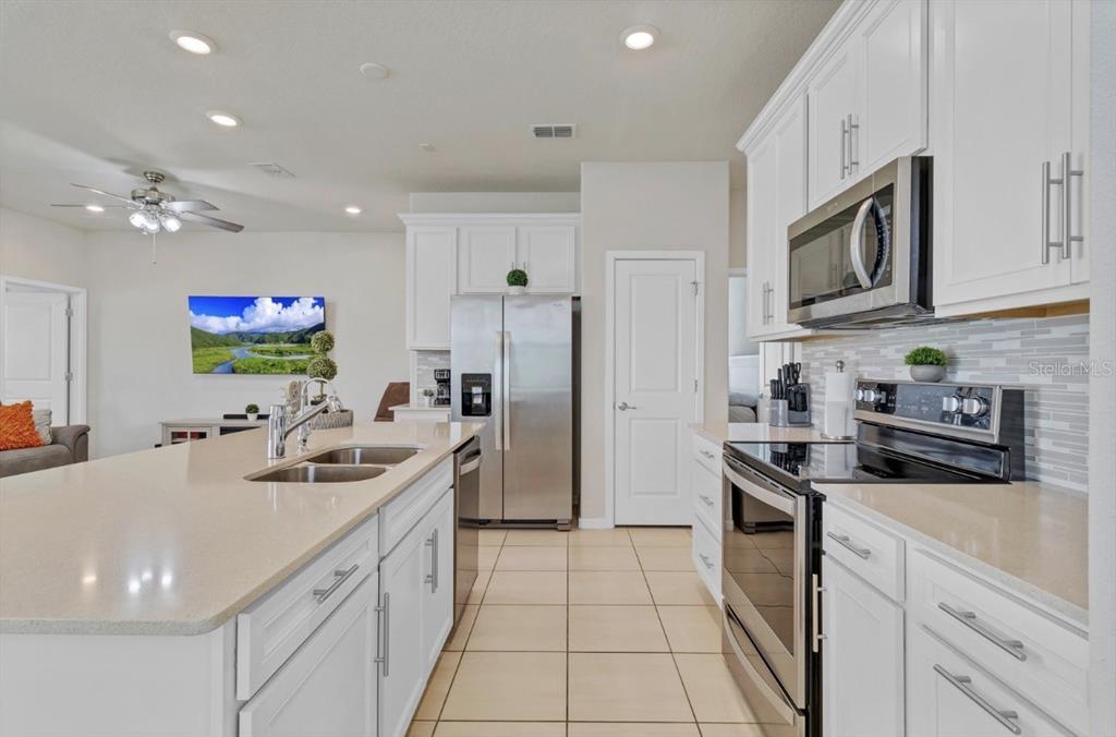 A kitchen with white cabinets, stainless steel appliances, and a large island with a sink — 1872 SUMMER SERENITY DRIVE, KISSIMMEE, FL