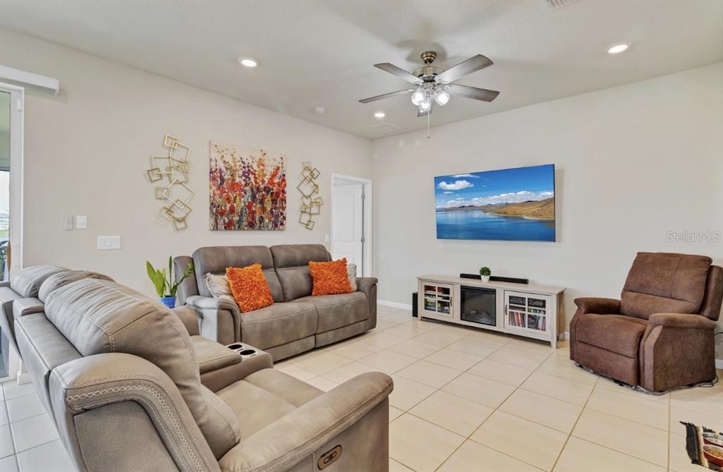 A living room features a gray sofa, a brown recliner, a television, and tile flooring — 1872 SUMMER SERENITY DRIVE, KISSIMMEE, FL