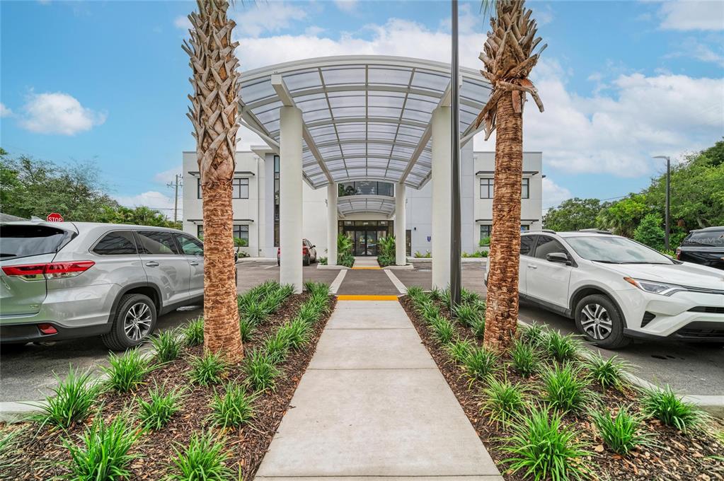 A concrete walkway leads to the entrance of a commercial building under a curved canopy — 201 5TH AVENUE DRIVE E, BRADENTON, FL