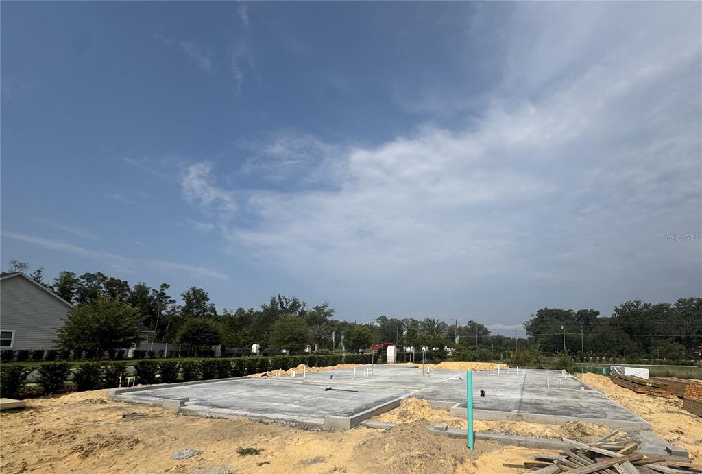 A concrete slab foundation sits on a cleared construction lot under a blue sky — 801 SW 144TH DRIVE, NEWBERRY, FL