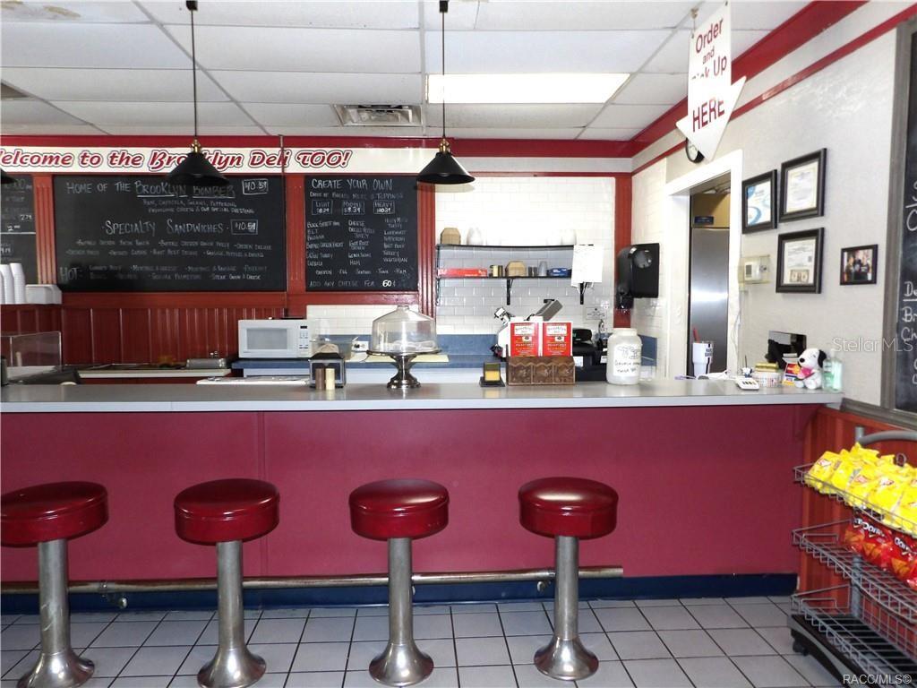 A deli counter features red stools, a menu board, and a tiled floor — 3360 E GULF TO LAKE HIGHWAY, INVERNESS, FL