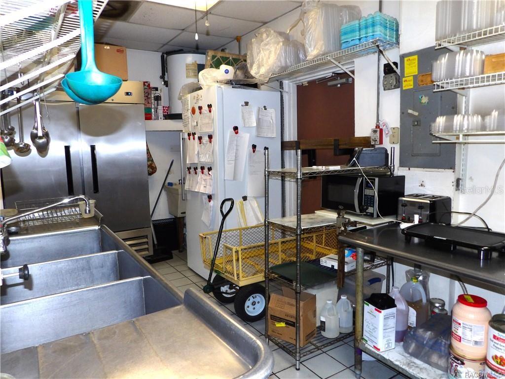 A commercial kitchen features a stainless steel sink, a refrigerator, and metal shelving units — 3360 E GULF TO LAKE HIGHWAY, INVERNESS, FL
