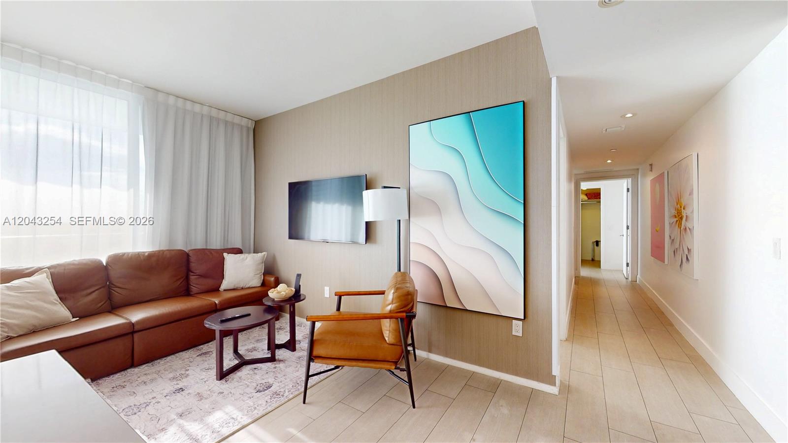 A living room features a brown leather sofa, a matching armchair, and abstract wall art — 4010 S Ocean Dr # R1004, Hollywood FL 33019, HOLLYWOOD, FL
