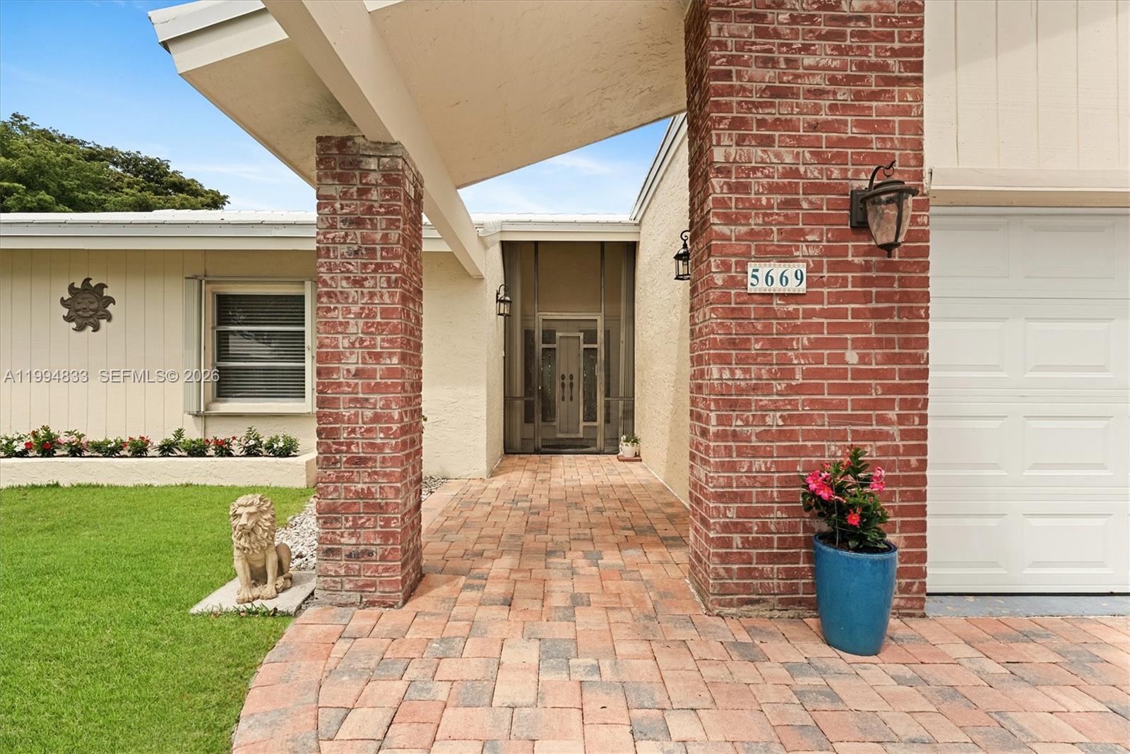 A brick-columned entryway leads to a screened front door with a paved walkway — 5669 Pinecrest Cir, Boca Raton FL 33433, BOCA RATON, FL