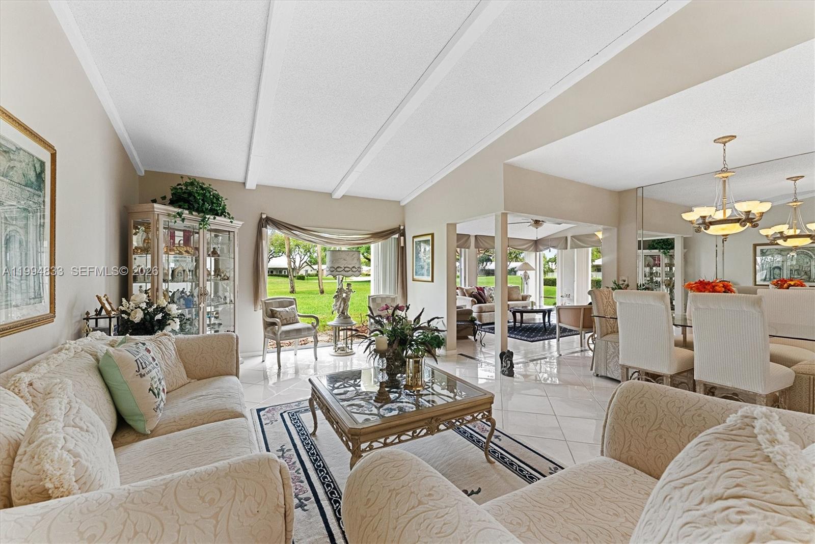 A living room with vaulted ceilings, tile floors, and a view of a grassy yard — 5669 Pinecrest Cir, Boca Raton FL 33433, BOCA RATON, FL