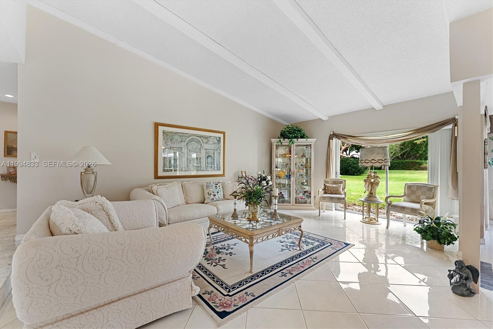 A living room features a vaulted ceiling, tile flooring, and a large sliding glass door — 5669 Pinecrest Cir, Boca Raton FL 33433, BOCA RATON, FL