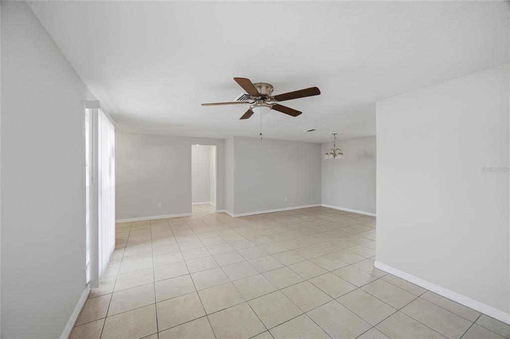 An open-concept living and dining area features light gray walls, tile flooring, and ceiling fans — 6204 WESTPORT DRIVE, PORT RICHEY, FL