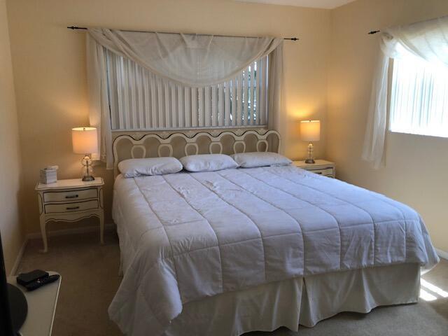 A bedroom features a king-sized bed with white bedding, two nightstands, and window treatments — 5501 NW 2nd Avenue, Boca Raton FL 33487, BOCA RATON, FL