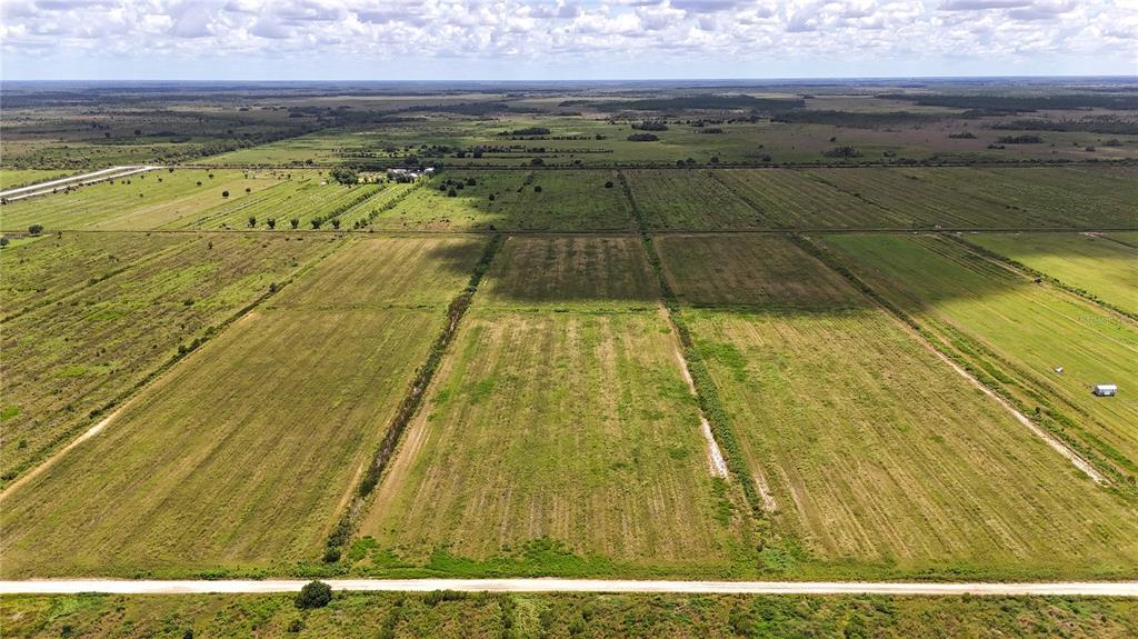 An aerial view shows large, flat, grassy agricultural fields divided by dirt roads and ditches — 5595 1ST ROAD, LABELLE, FL