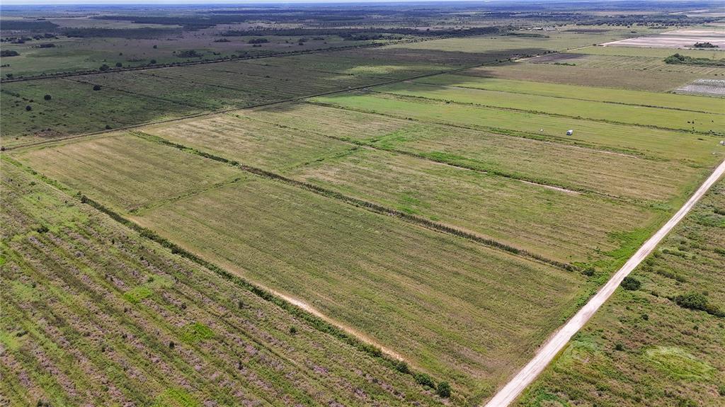 An aerial view shows a large, flat, grassy field bordered by a dirt road — 5595 1ST ROAD, LABELLE, FL