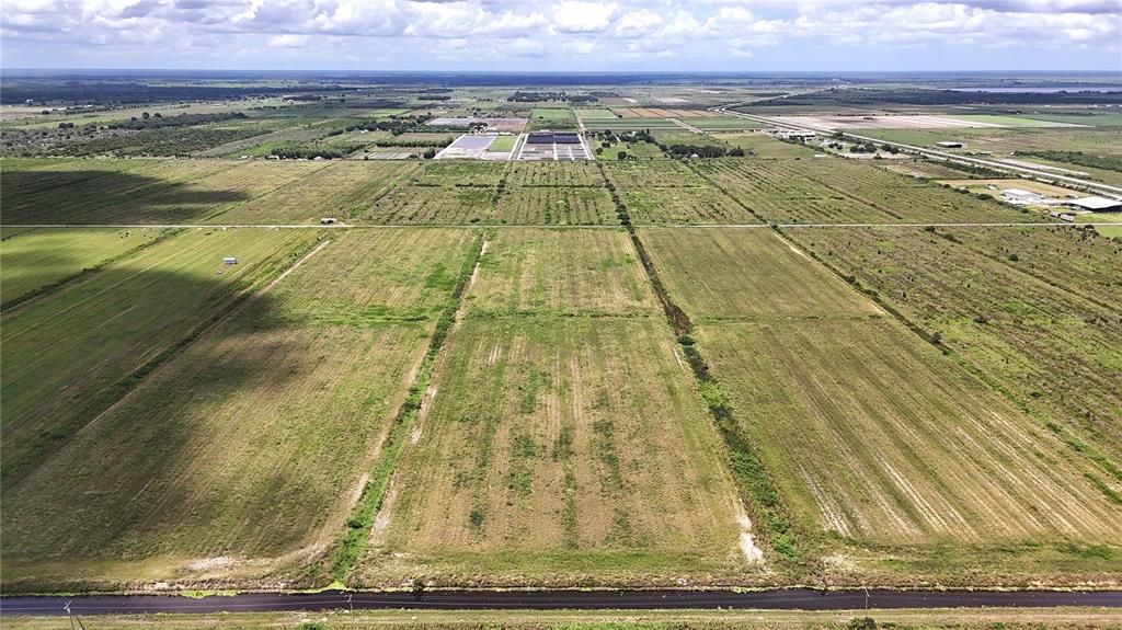 An aerial view shows large, flat agricultural fields divided by dirt roads and drainage ditches — 5595 1ST ROAD, LABELLE, FL